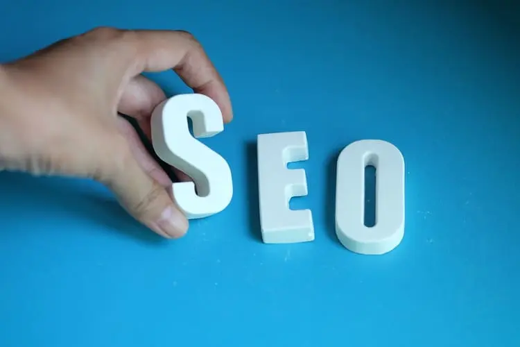 Letras SEO sendo organizadas manualmente representando otimização para mecanismos de busca